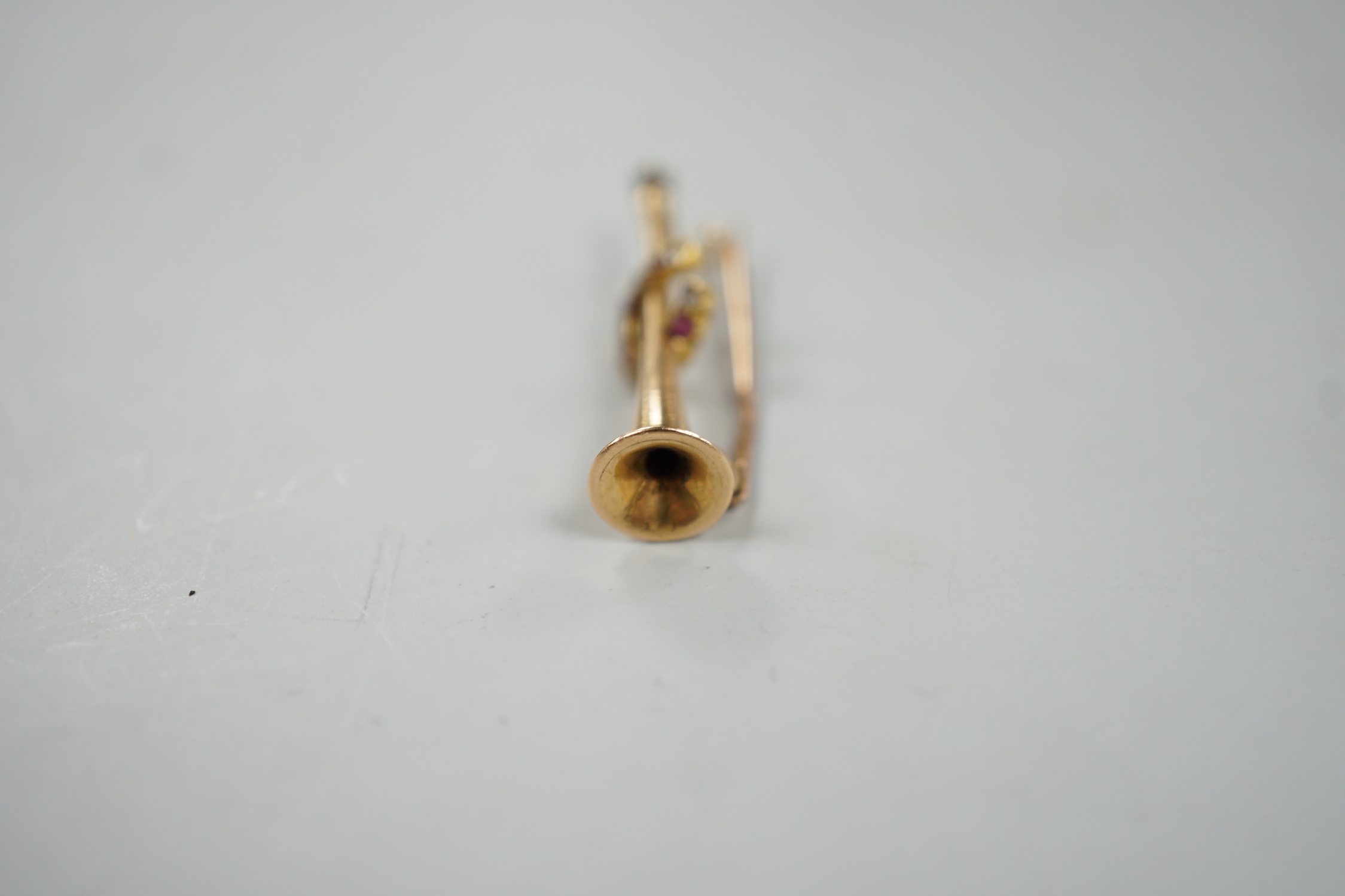 An Edwardian yellow metal, ruby and diamond set hunting horn and horseshoe brooch, 37mm, gross weight 2.6 grams.